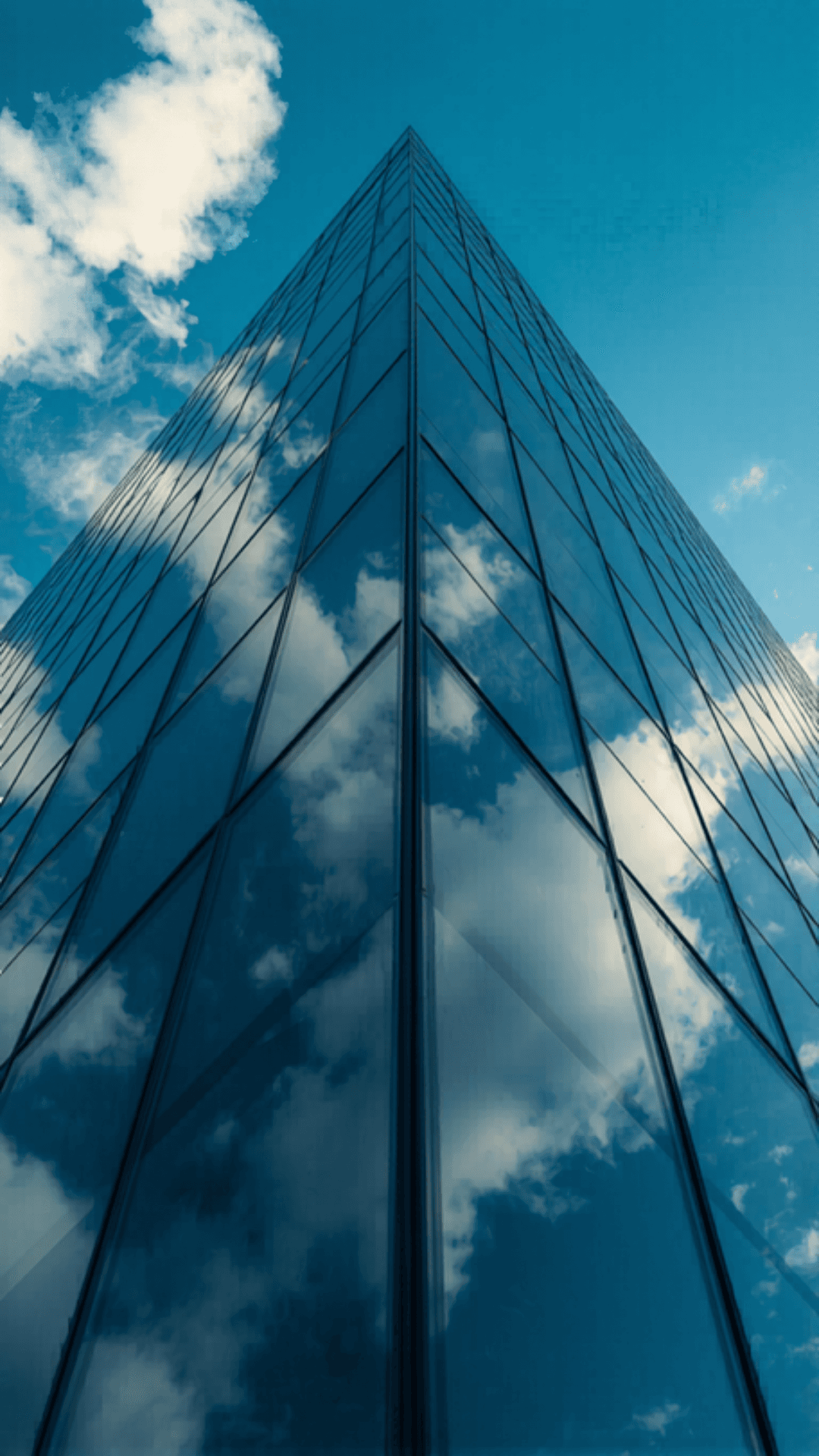 Edificio moderno de cristal con el cielo y nubes reflejados — representación de solidez institucional